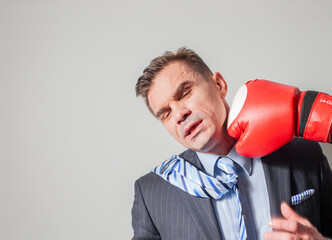 Businessman man gets hit in the face with a boxing glove