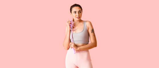 Sporty young woman with skipping rope on color background