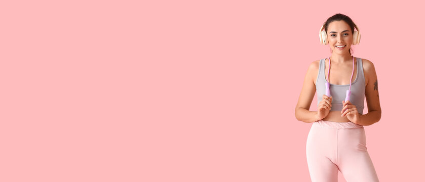 Sporty young woman with skipping rope and headphones on color background