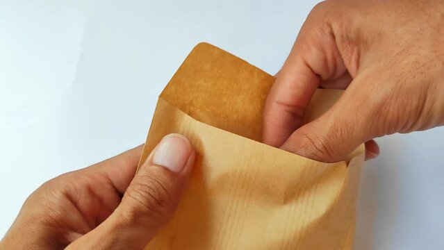 The hand of the man who took out a bunch of 100,000 rupiah bills from the brown envelope. Opened the salary envelope.