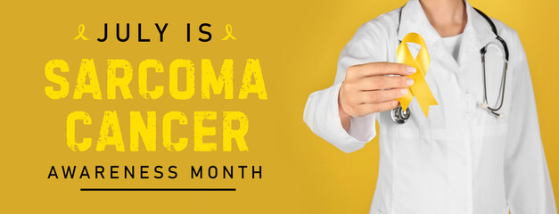Doctor with yellow ribbon on color background. Cancer awareness concept