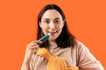 Young woman smoking electronic cigar on orange background, closeup