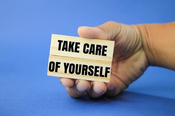 hand holding a stick with the words take care of yourself. the concept of self-care