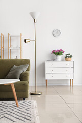 Vase with tulips and bonsai on drawers in living room interior