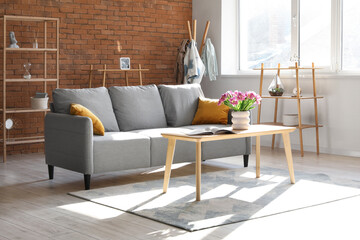 Interior of stylish living room with sofa and tulips on table