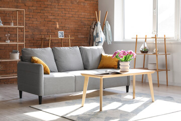 Interior of stylish living room with sofa and tulips on table