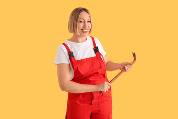 Female worker with crowbar on yellow background