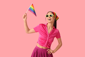 Beautiful young woman in sunglasses with LGBT flag on pink background