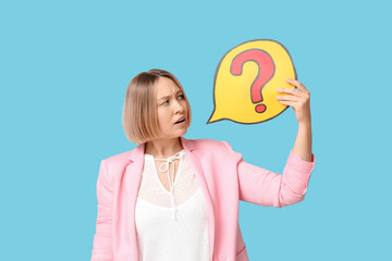 Shocked adult woman holding speech bubble with question mark on blue background