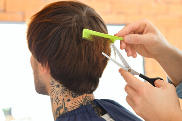Male hairdresser cutting client's hair in barbershop, closeup