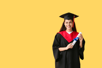 Happy female graduate with diploma on yellow background