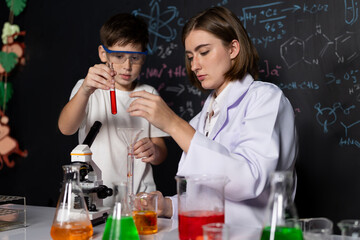Teacher support schoolboy in laboratory. Schoolboy and teacher stand and experiment about science...