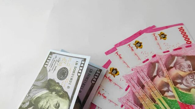 The hand of the man who counted the 100 amarika dollars bills and placed them one by one next to the 100,000 rupiah bills on the table.
