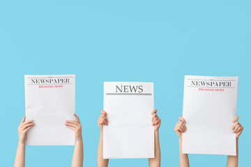 Women holding newspapers against color background