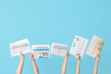 Women holding newspapers against color background