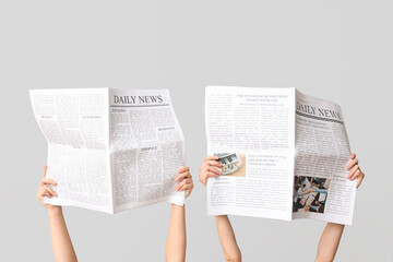 Female hands with newspapers on grey background