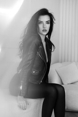 Girl in a black leather jacket sitting on the sofa