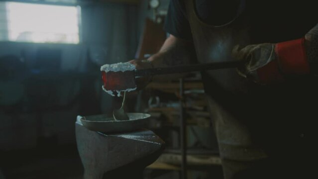 Blacksmith working with hot metal and borax powder in a forge