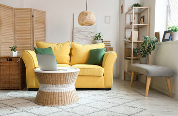 Interior of stylish living room with yellow sofa, coffee table and laptop