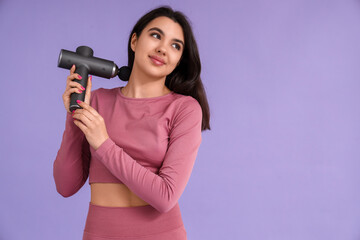 Sporty young woman massaging her neck with percussive massager on lilac background
