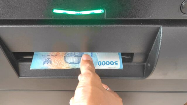 The hand of the man who took 50,000 rupiah at the ATM machine. Retrieval of money in the machine.