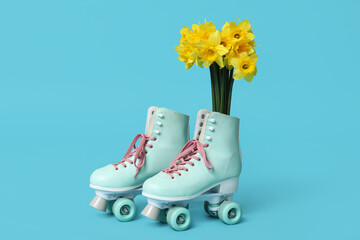 Vintage roller skates with bouquet of beautiful narcissus flowers on blue background