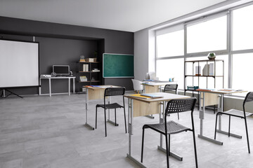 Interior of empty classroom with desks and chalkboard