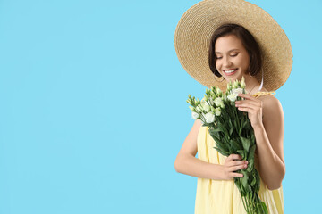 Young woman in straw hat with eustoma flowers on blue background