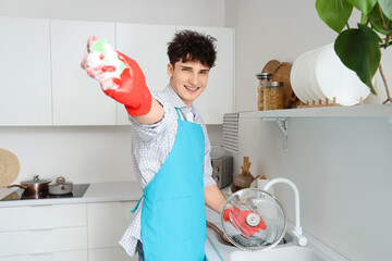 Male janitor washing dishes in kitchen