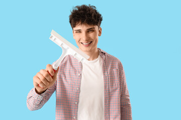 Young man with squeegee on blue background