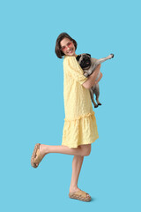 Young woman with cute pug dog on blue background