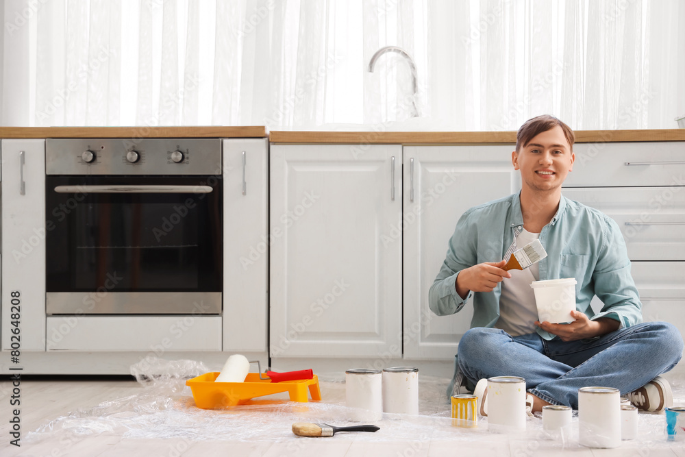 Canvas Prints Young man with brush and paint can sitting in kitchen