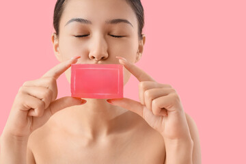 Young Asian woman with soap on pink background, closeup