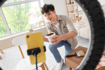 Male blogger with brush painting furniture while recording video at home