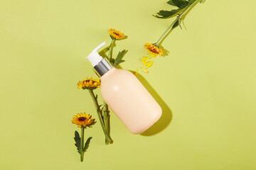 Unbranded pump bottle in beige color decorated with Calendula flowers. Top view. Calendula contains...
