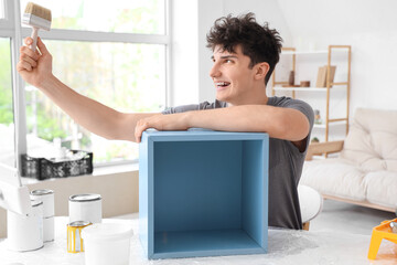 Young man with brush painting box at home