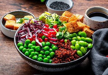 Vegan Buddha Bowl for balanced diet with tofu, quinoa, vegetables and legumes. Wooden table...