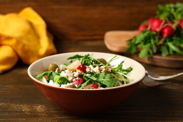 Bowl of tasty salad with radish on wooden table