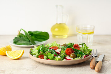 Plate with tasty salad and cutlery on light table