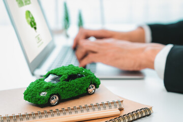 Businessman working in office developing plan or business project on eco-friendly ev car using net...