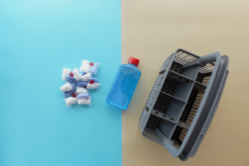 A stack of dishwasher tablets and a bottle of detergent on a blue background