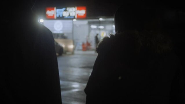 Two men walking up to a grocery store at night