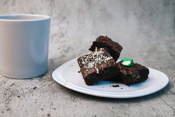 A Plate of Brownies Cake with A Cup of Coffee Isolated on Gray Background 