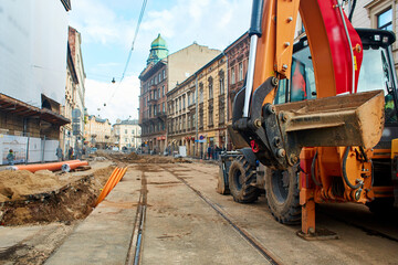 Sewerage and water supply repairs in the old streets of Europe. An excavator stands on a dug-up...