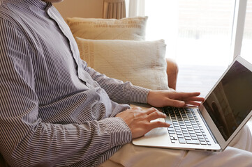 Naklejka premium リビングでパソコンを使っている若い男性