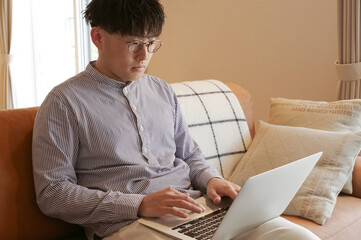 リビングでパソコンを使っている若い男性