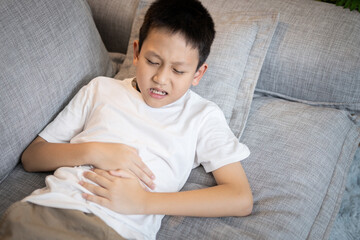 Sick asian child boy suffering from Gastritis,Gastric ulcer,stomach ache,inflammation of the stomach and intestines,symptoms of Gastroenteritis,infection of bacterial or viral,soreness,pain in abdomen