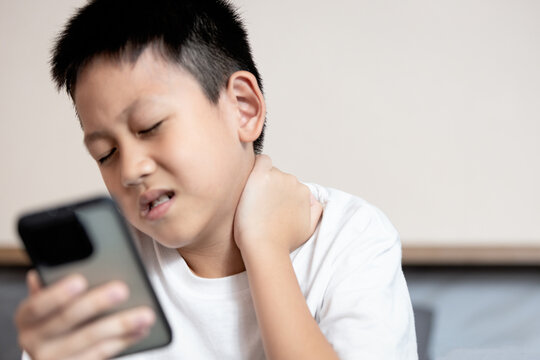 Asian boy looking at phone screen,tilting his head down for long time,Text Neck Syndrome,Smartphone or Mobile syndrome,stiff and pain in neck muscle,aching and tightness in nape of neck and shoulder