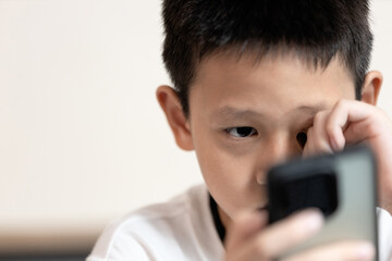 Child boy looking phone screen,unable to see clearly,Amblyopia disease,blurred vision or symptoms...