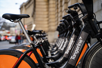 Fototapeta premium Tangerine Electric Bikes in Downtown Toronto. Toronto, Canada - April 29, 2024.